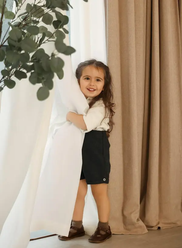 Little girl in a white blouse beside cream curtains, studio photography by Photoholic, Monsey NY