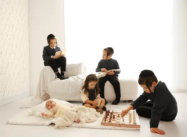 Siblings playing chess and reading in a bright white studio, studio photography by Photoholic, Monsey NY