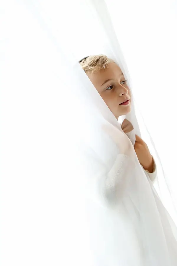 Little boy peeking out from behind a white curtain, studio photography by Photoholic, Monsey NY