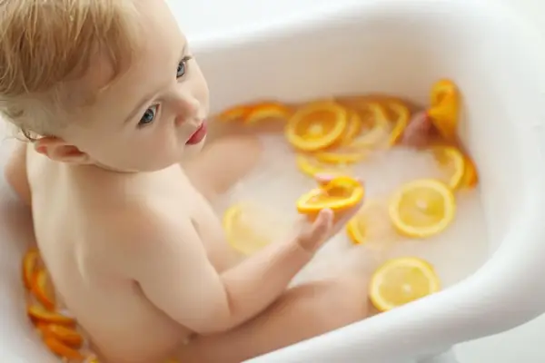 Baby in a milk bath with orange slices, studio photography by Photoholic, Monsey NY