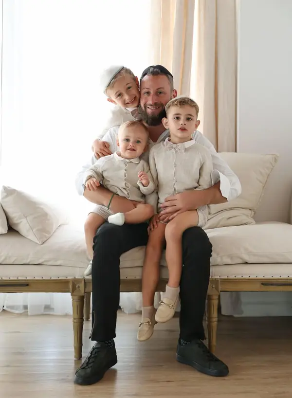 Father holding his three young children on a sofa, studio photography by Photoholic, Monsey NY